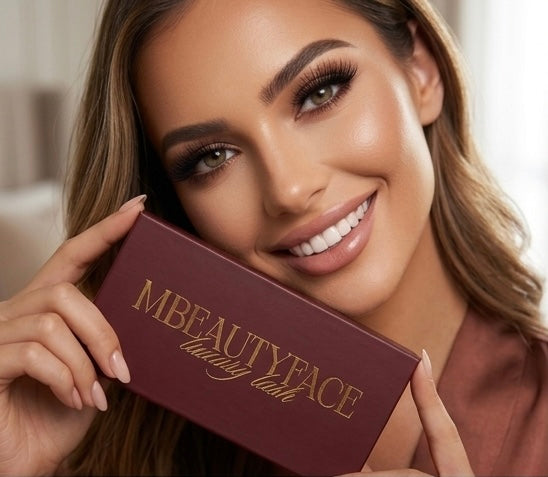 Femme souriante tenant une boîte de cils magnétiques haut de gamme MBEAUTYFACE, packaging couleur bordeaux et logo doré, regard mis en valeur par des faux-cils fournis.